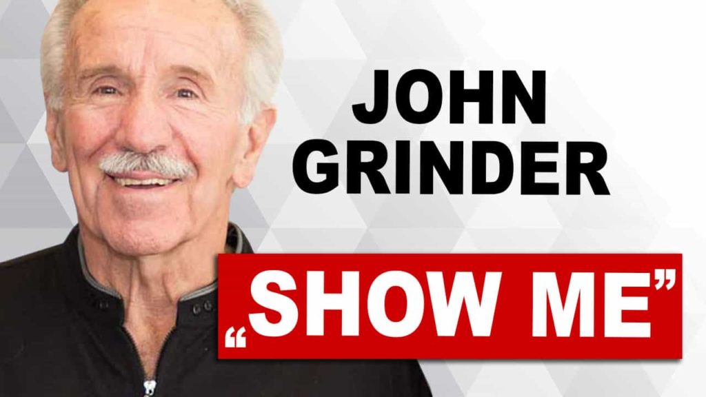 John Grinder nebem dem Schriftzug "Show me"
